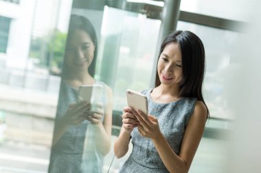 Pencere yansıması ile cep telefonu kullanarak iş kadını