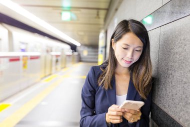 tren istasyonunda cep telefonu kullanan kadın