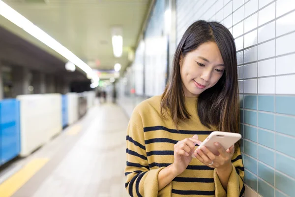 Жінка працює на мобільному телефоні на вокзалі — стокове фото