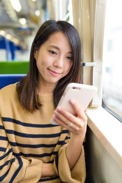 Жінка дивиться на мобільний телефон в поїзді — стокове фото