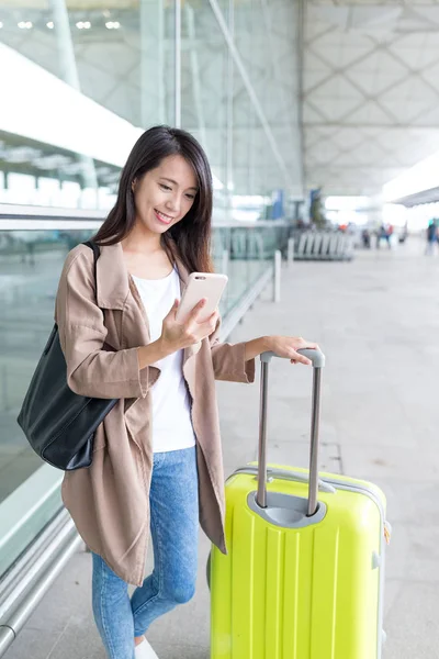 Woman using cellphone and luggage at airport — Stock Photo, Image