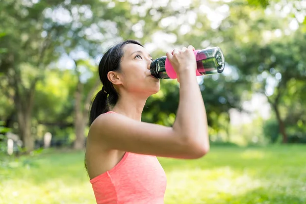 スポーツ女性は、公園で水を飲む — ストック写真