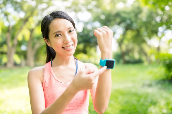 年轻女子在公园中使用 smartwatch — 图库照片