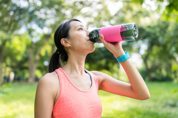 スポーツ女性は、公園で水を飲む — ストック写真