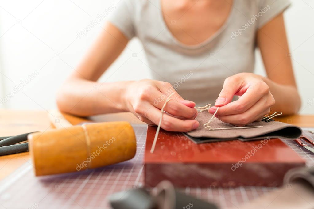 Woman making bag with leather