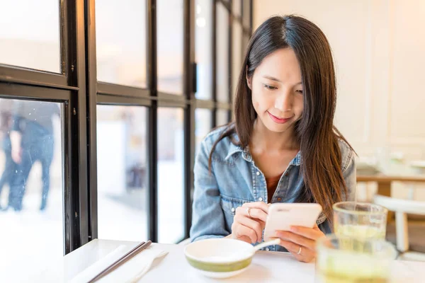 Женщина смотрит на сотовый телефон в ресторане — стоковое фото