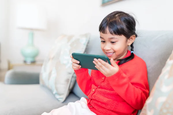 Liten flicka spela mobiltelefon hemma — Stockfoto