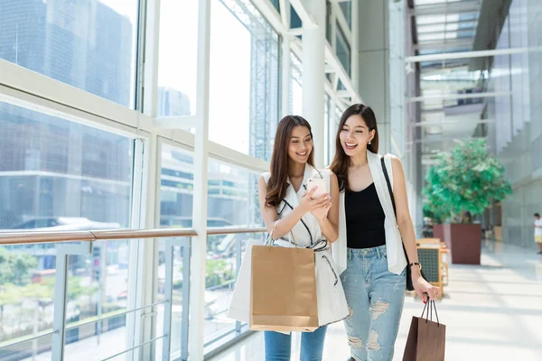 Vänner gå shopping och använda mobiltelefon tillsammans — Stockfoto