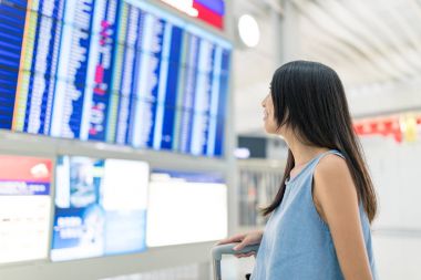 Kadın seyahat ve havaalanında uçuş programı bakarak