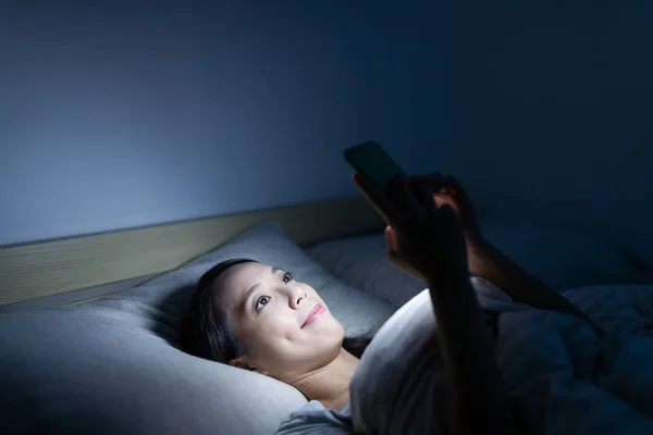 Женщина с мобильного телефона на кровати — стоковое фото