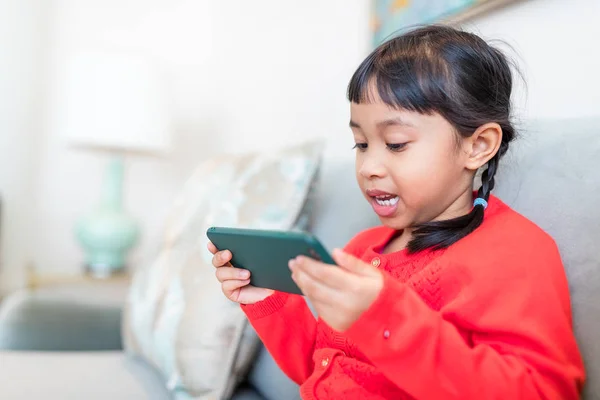 Flicka spela på mobiltelefonen hemma — Stockfoto