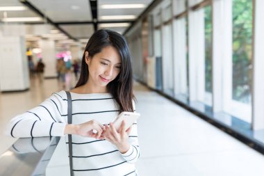 İstasyonda cep telefonu kullanan kadın