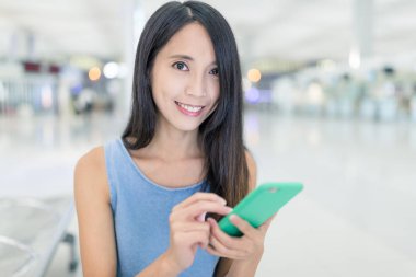 Havaalanında cep telefonu üzerinde çalışan kadın