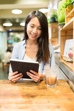 bir kafede, tablet bilgisayar kullanan kadın