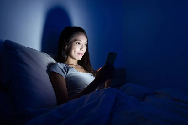 Mujer usando teléfono móvil en la cama por la noche —  Fotos de Stock