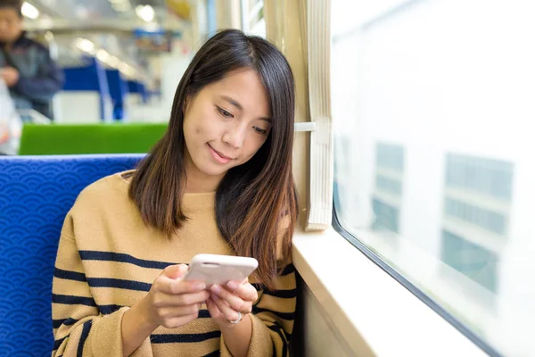 Žena používající mobilní telefon a přijetí vlaku — Stock fotografie