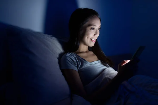 Mujer usando celular en la cama por la noche —  Fotos de Stock