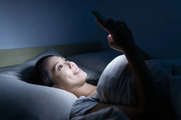 Wanita menggunakan smartphone di tempat tidur — Stok Foto
