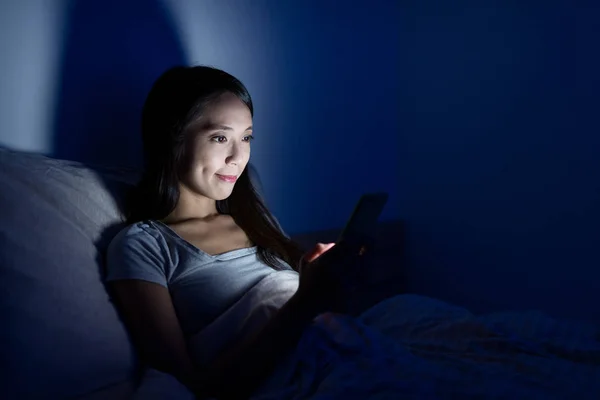 Mulher usando celular na cama à noite — Fotografia de Stock