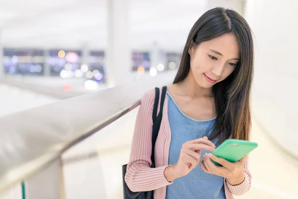 Vrouw kijken naar mobiele telefoon in luchthaven — Stockfoto