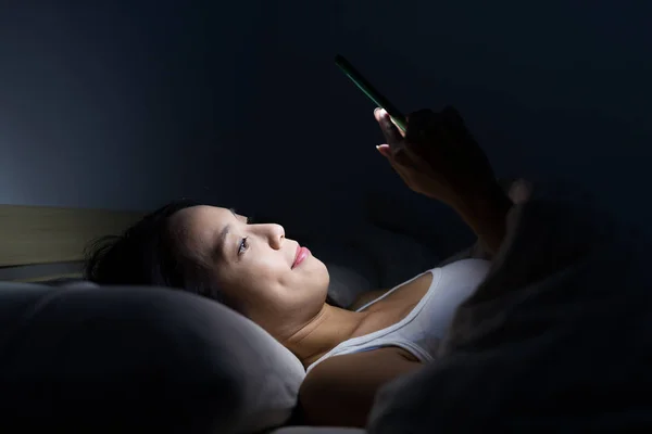 Mobiltelefont használó nő az ágyban — Stock Fotó