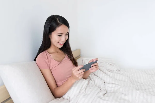 Mulher jogar jogo no celular na cama — Fotografia de Stock