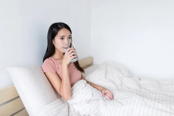 Frau trinkt Wasser auf dem Bett — Stockfoto