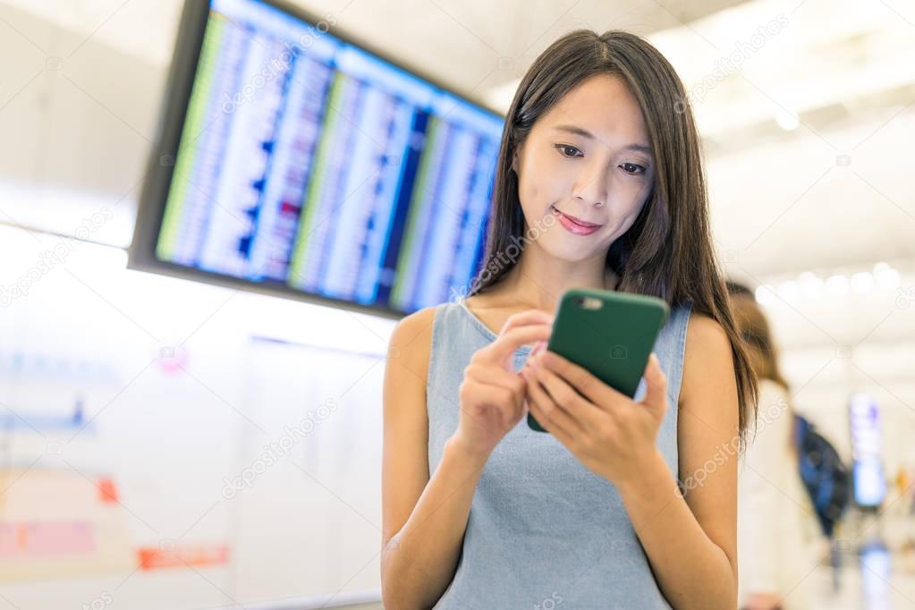Woman checking time table on mobile phone in airport
