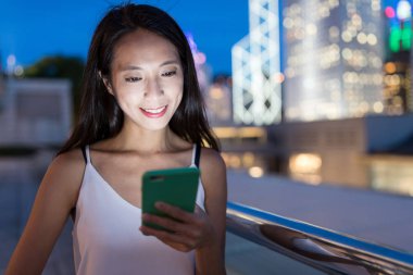 Geceleri cep telefonu kullanan bir kadın.