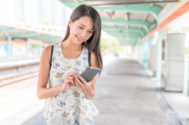 Tren istasyonunda cep telefonu kullanan kadın 