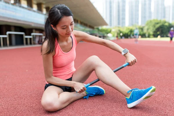 Donna sportiva con rullo bastone sulle gambe — Foto Stock