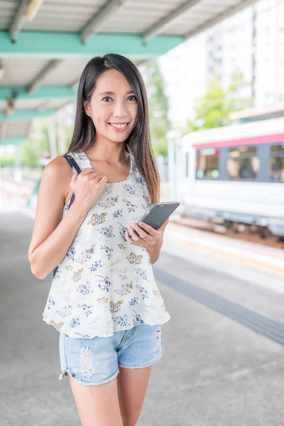 Smartphone tren istasyonu üzerinde tutan kadın