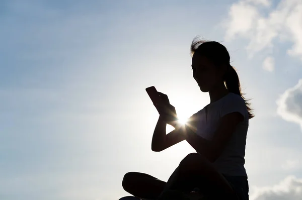 Sziluettjét nő mobiltelefon segítségével — Stock Fotó