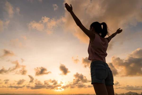 Femme levant la main sous le coucher du soleil — Photo