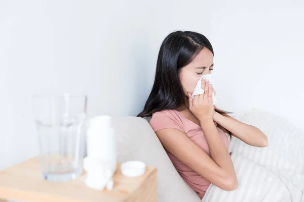 Woman sneezing on bed