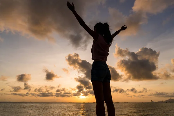Vrouw hand omhoog onder zonsondergang — Stockfoto