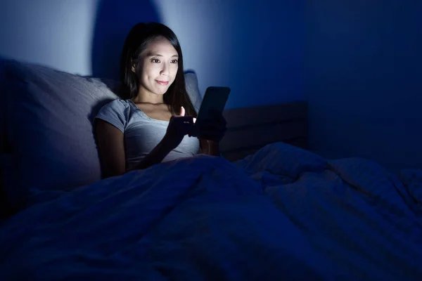 Mujer trabajando en el teléfono móvil en la cama —  Fotos de Stock