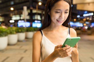 Geceleri cep telefonu kullanan bir kadın.