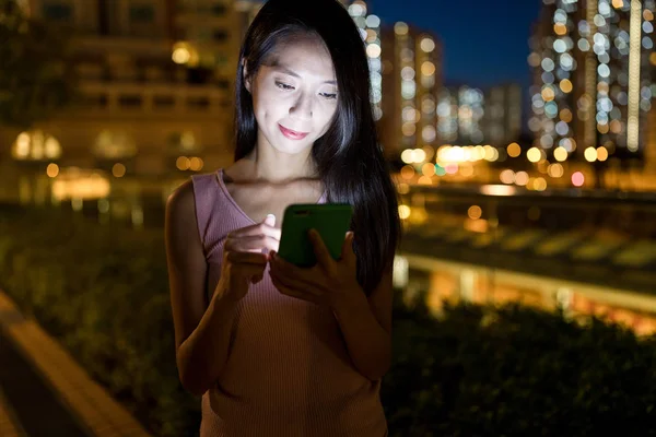 Žena používající mobilní telefon ve městě v noci — Stock fotografie