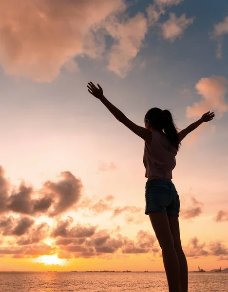 Mulher abre os braços sob o pôr do sol — Fotografia de Stock
