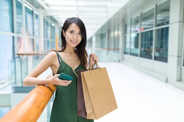 Frau kauft mit Handy und Papiertüte ein — Stockfoto