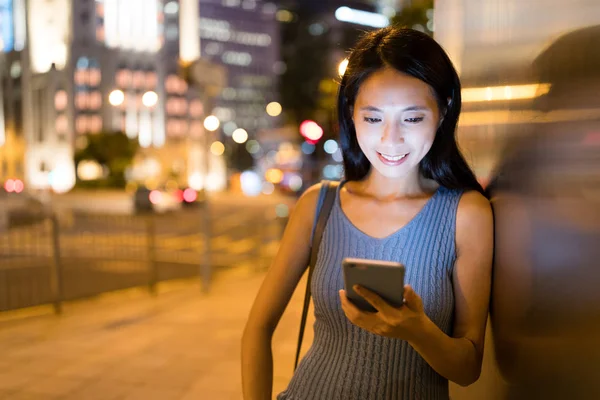 Mujer enviando sms en el teléfono celular por la noche — Foto de Stock