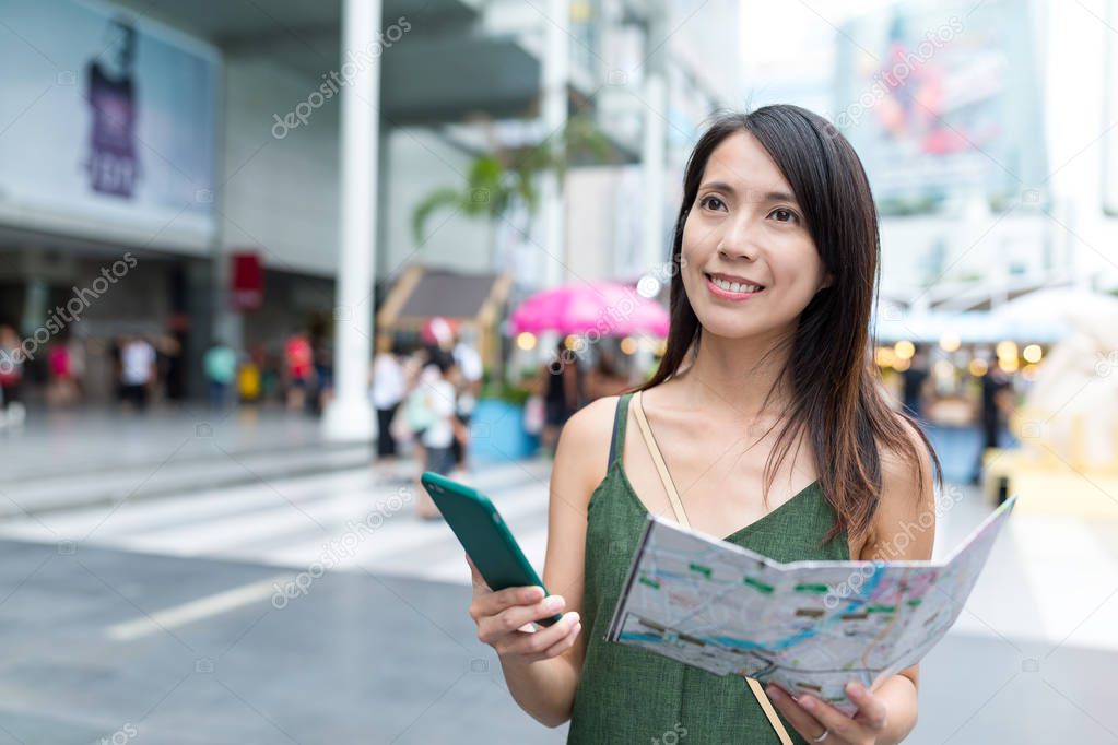 Tourist using cellphone and holding city map 
