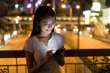 Geceleri cep telefonu kullanan bir kadın.