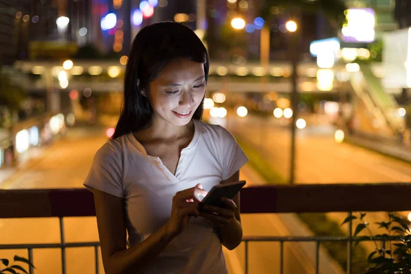 Geceleri cep telefonu kullanan bir kadın.