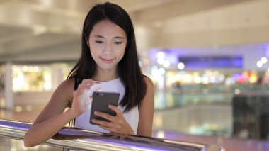 Alışveriş merkezinde cep telefonu kullanan kadın