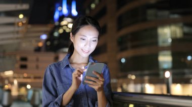 Geceleri cep telefonu kullanan bir kadın. 