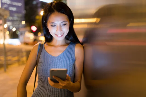 Mujer usando celular en la ciudad por la noche — Foto de Stock