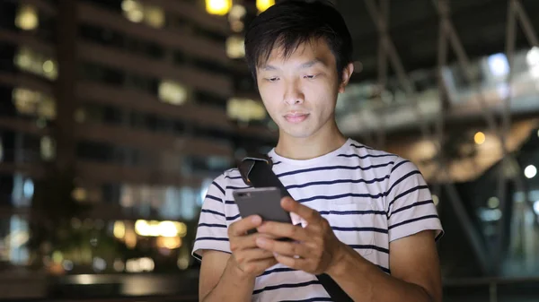 Человек смотрит на мобильный телефон ночью — стоковое фото