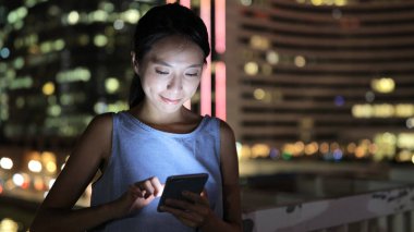 Geceleri cep telefonu kullanan bir kadın.